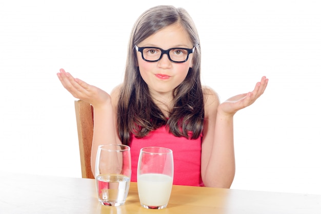 Una niña puede elegir entre un vaso de agua y un vaso de leche en blanco