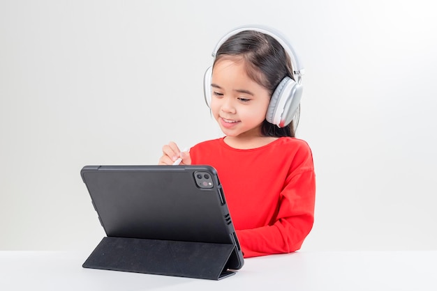 La niña se puso los auriculares y tiene una clase distante de videollamadas con el maestro que estudia la educación en el hogar en línea