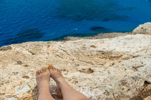 Una niña puso sus pies en la ladera rocosa de la montaña cerca del mar Mediterráneo
