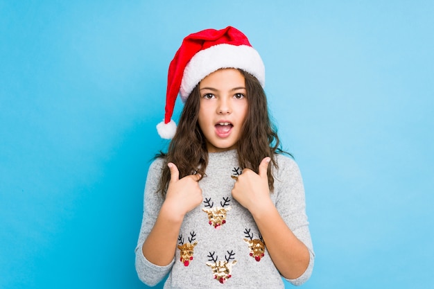 La niña que celebraba el día de Navidad sorprendió señalar con el dedo, sonriendo ampliamente.