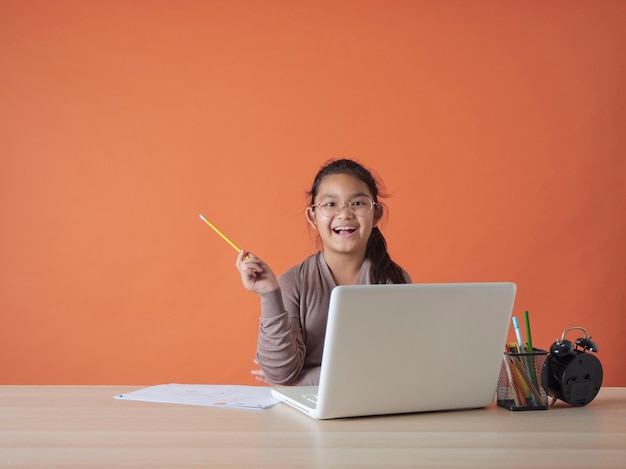 Niña que estudia en línea con el portátil en casa.