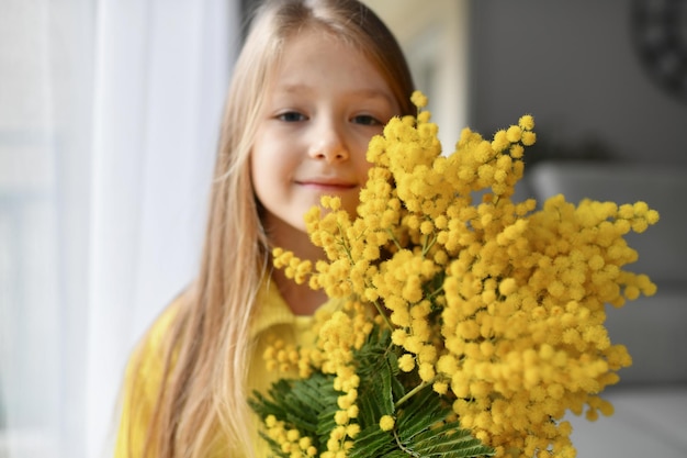 Una niña que huele a mimosa amarilla en primavera