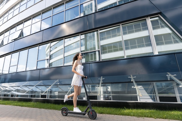 Una niña que monta un scooter eléctrico en la ciudad.