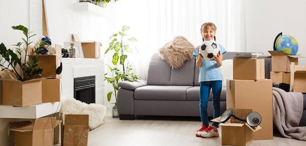 Niña que se muda a una casa nueva, cerca de una caja de cartón.