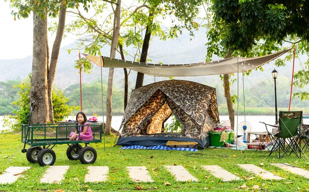 Niña que se sienta en carro mientras que va a acampar.