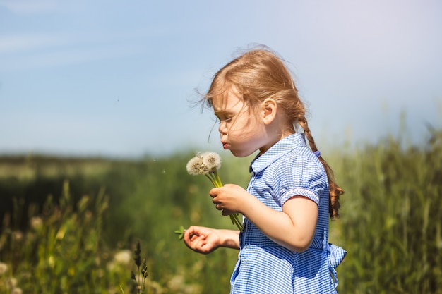 niña que sopla sobre un diente de león