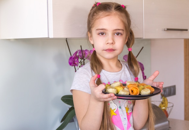 Niña que sostiene la placa con bolas de masa hervida coloridas.