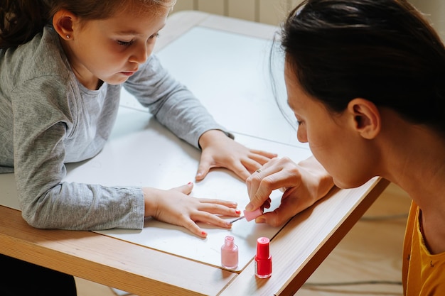 Niña a la que su madre le pinta las uñas