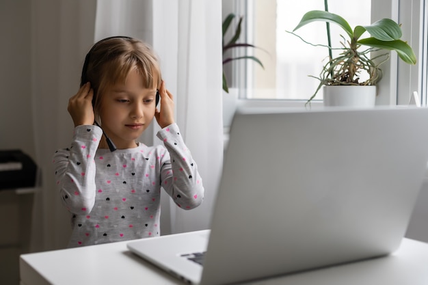 Niña que usa el chat de video en la computadora portátil en casa. Espacio para texto