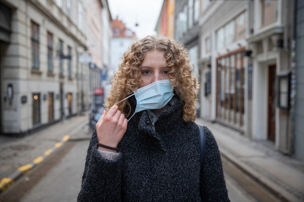 Niña se quita la mascarilla quirúrgica que usa para protegerse de la pandemia de coronavirus.