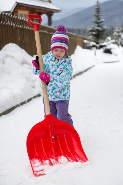 Foto la niña quita la nieve en el patio