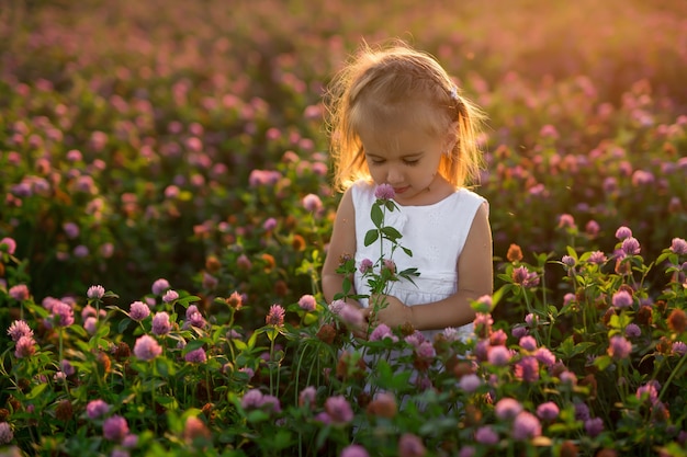 Una niña con un ramo de flores en un campo de tréboles es picada por mosquitos