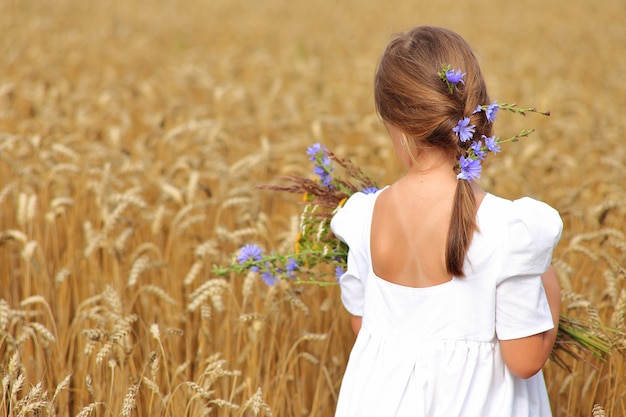 Niña con un ramo de flores silvestres en el campo