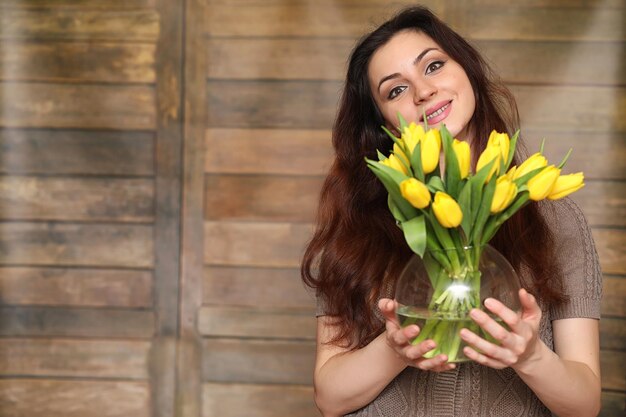 Niña con un ramo de tulipanes amarillos Niña con un regalo de flores en un jarrón Un regalo para niñas en unas vacaciones femeninas con tulipanes amarillos en el suelo