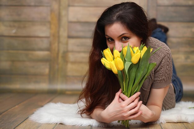Niña con un ramo de tulipanes amarillos Niña con un regalo de flores en un jarrón Un regalo para niñas en unas vacaciones femeninas con tulipanes amarillos en el suelo