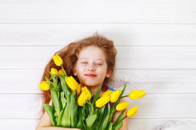 Niña con ramo de tulipanes.