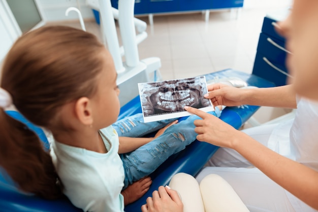 Una niña en la recepción de un dentista con sus padres.