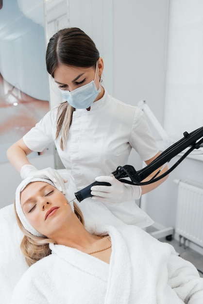 Una niña recibe un peeling de carbón para la piel de la cara en un salón de belleza Los pulsos de láser limpian la piel Cosmetología de hardware El proceso de fototermólisis que calienta la piel