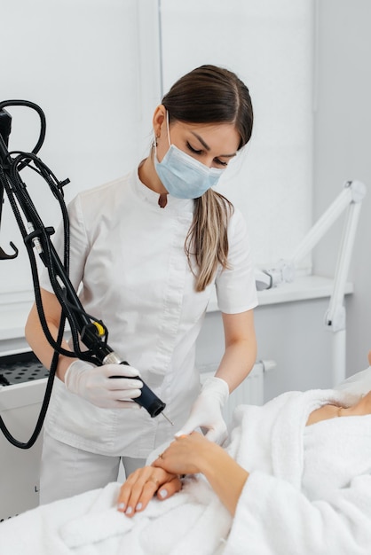 Foto una niña recibe un peeling de carbón para la piel de sus manos en un salón de belleza los pulsos de láser limpian la piel cosmetología de hardware el proceso de fototermólisis que calienta la piel