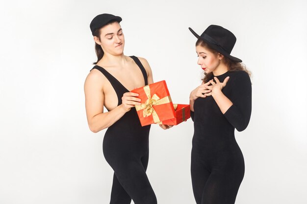 Niña recibe un regalo de cumpleaños de un hombre adulto joven. Foto de estudio, aislado sobre fondo blanco.