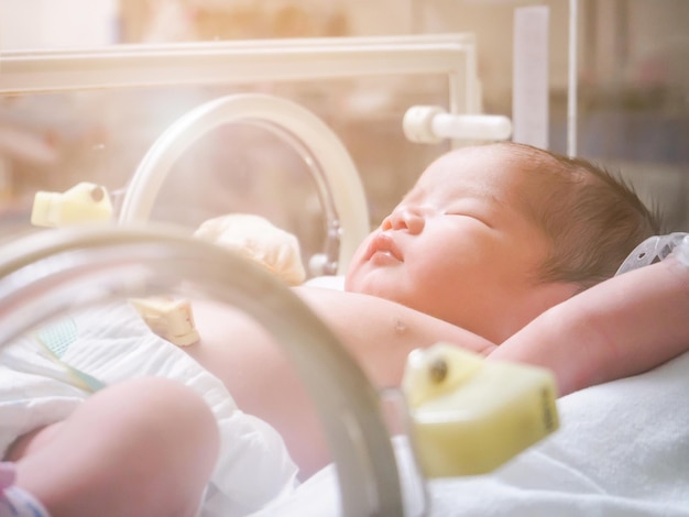 Niña recién nacida dentro de la incubadora en la sala de postparto del hospital