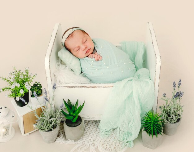 Niña recién nacida durmiendo en una cama pequeña decorada con plantas. Adorable niño infantil niño durmiendo la siesta con corona