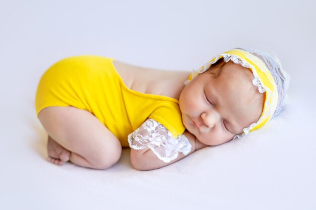 Foto niña recién nacida en un traje amarillo durmiendo dulcemente en su estómago en un retrato de primer plano