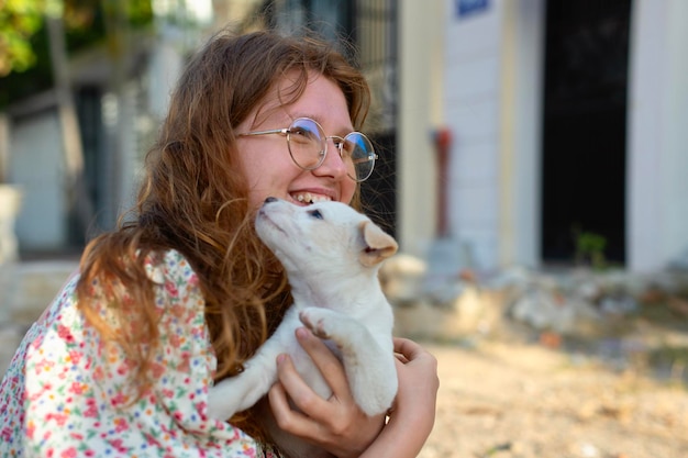Niña recogió a un perro sin hogar y sosteniendo en sus brazos en la calle la mano de una persona acaricia al perro abandonado asustado cachorro sin hogar en un refugio para perros