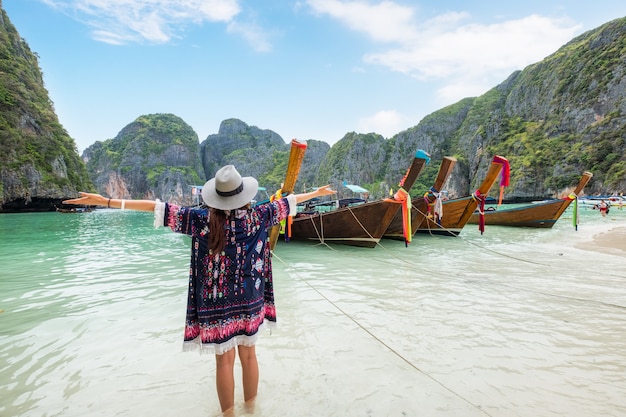 Niña refrescante con botes de cola larga de madera en Maya Bay, Krabi, Tailandia