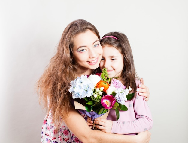 La niña regala un ramo de flores de primavera a una mujer joven