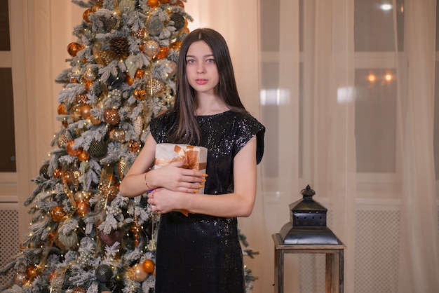 niña con un regalo cerca del árbol de navidad en navidad