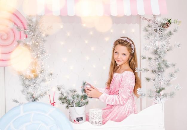 Niña con un regalo en sus manos en el fondo de un árbol de Navidad