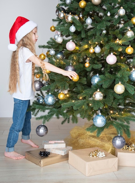 Una niña con regalos juega cerca del árbol de Navidad.