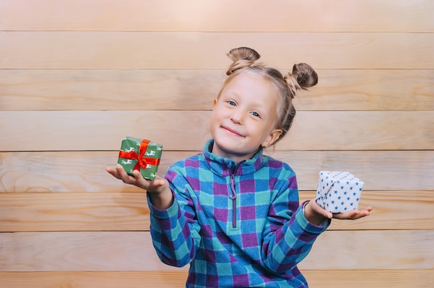 Niña con regalos en las manos en el fondo de tablas de madera.