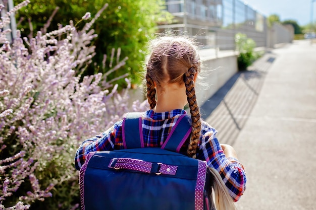 Foto niña de regreso a la escuela con mochila va a la escuela el primer día después de las vacaciones