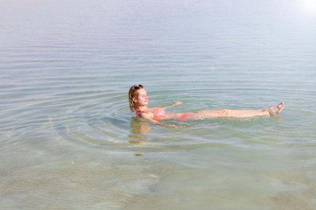 Foto niña se está relajando y nadando en el agua del mar muerto en israel mujer nadando en el mar muerto