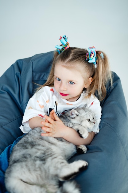 Niña relajándose en la cama con su gatito Niño besando a un gato