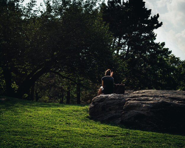 Niña relajándose en una roca en el parque central