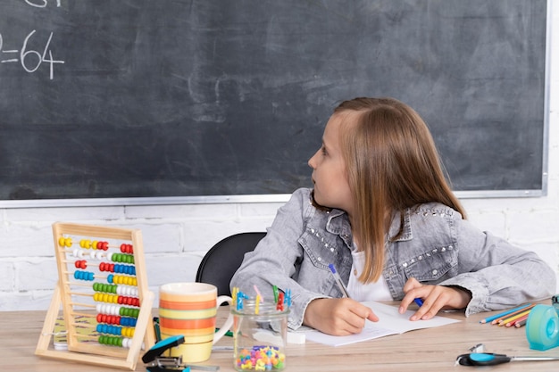 La niña resuelve la tarea dada en el aula la escolar escribe diligentemente en un cuaderno