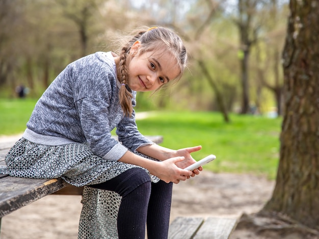 Una niña revisa su teléfono, sin prestar atención a la hermosa naturaleza que la rodea.