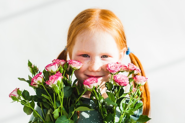 La niña se ríe, juega con su hermana, su familia, sostiene flores y hojas en sus manos.