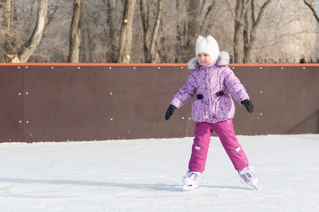 La niña se ríe y patina sobre el hielo.