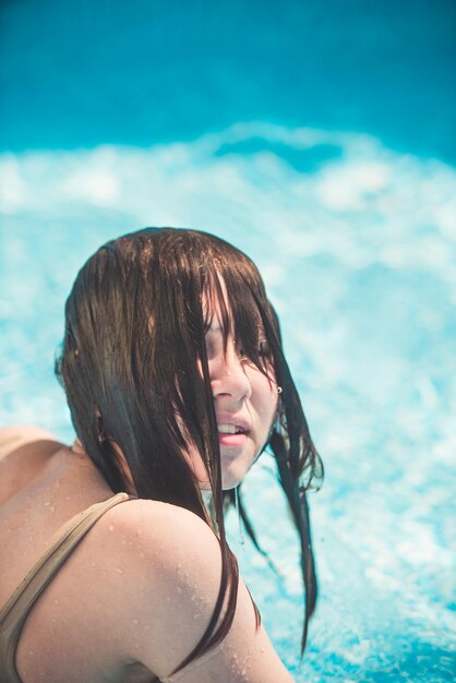 Una niña se ríe en las salpicaduras de agua en la piscina
