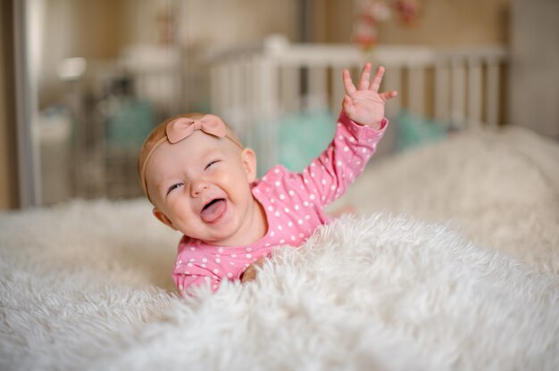 Niña riendo con un arco sobre su cabeza acostada en la cama