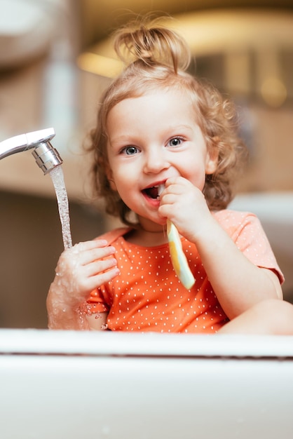 Niña riendo feliz cepillándose los dientes en el baño