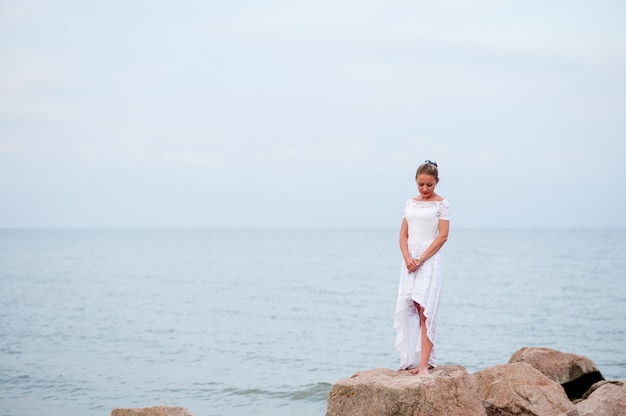 Niña en las rocas en el mar