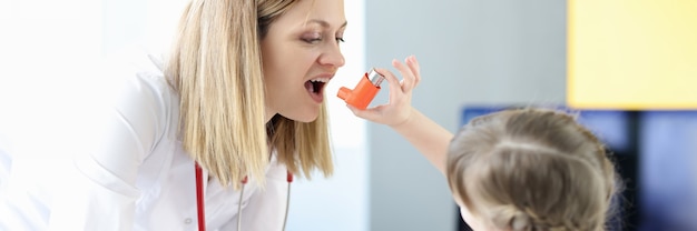 Niña rociando inhalador hormonal al médico en la clínica. Tratamiento del asma bronquial en el concepto de niños