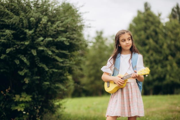 Niña rockera elegante y de moda con una guitarra, coletas multicolores de kanekalon. Foto de alta calidad.