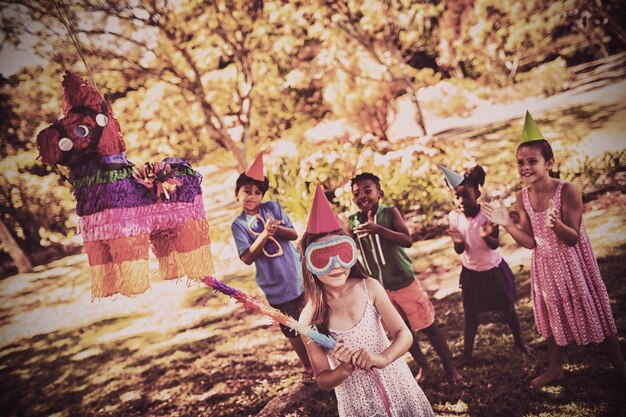 La niña va a romper la piñata por su cumpleaños.