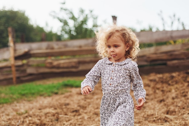 Una niña con ropa azul está en la granja en verano al aire libre